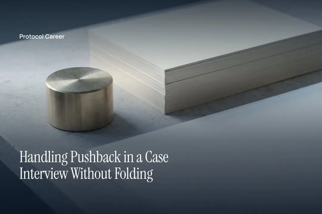 A small cylindrical brass weight sits beside a crisp stack of blank paper on a grey stone surface. Title: “Handling Pushback in a Case Interview Without Folding”, over the Protocol Career wordmark.