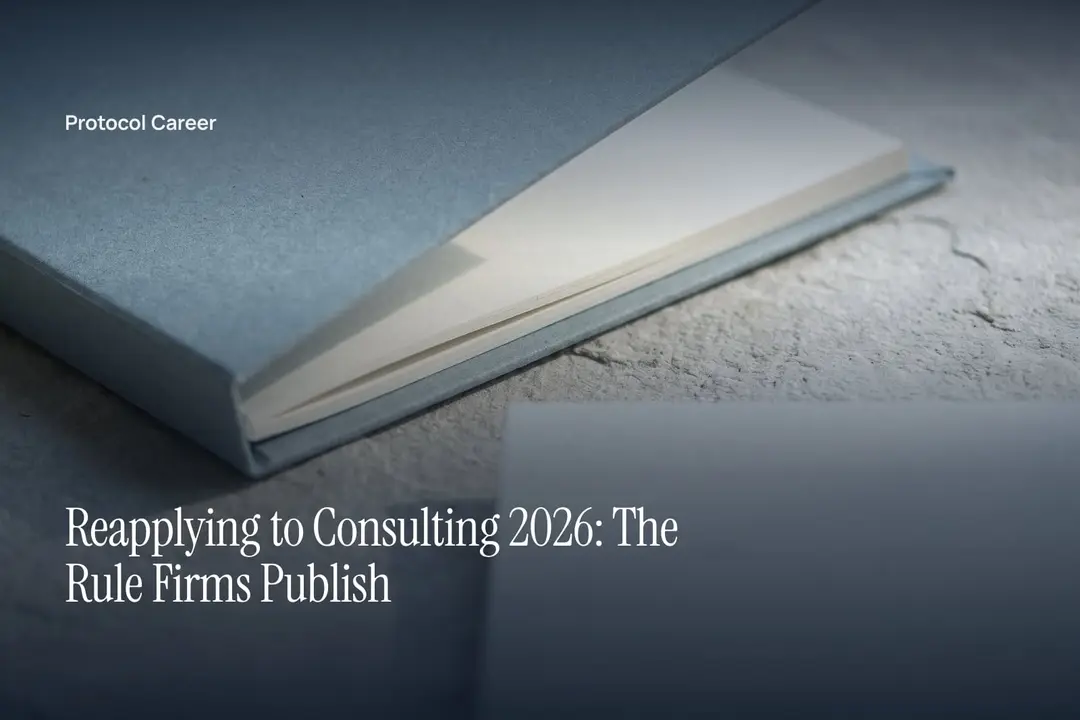 A minimalist cardstock folder with blank ivory sheets rests on a smooth stone surface under soft light. Title: “Reapplying to Consulting 2026: The Rule Firms Publish”, over the Protocol Career wordmark.